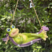 Hanging frog garden ornament in a purple hammock with a backyard garden background.