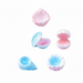 Five assorted miniature seashell figurines in pastel pink and blue colors, including a spiral conch and open clams, isolated on a white background.