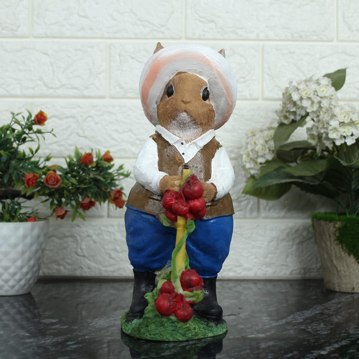 Hand-painted figurine of a rabbit dressed as a gardener in a hat, white shirt, and blue trousers, holding red berries