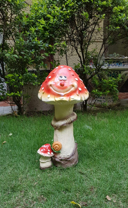 A colorful garden statue of a large red-and-white capped mushroom with a happy face, a smaller mushroom, and a snail
