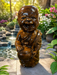 Handcrafted 14-inch polished tiger eye stone laughing monk statue holding a bowl in a garden setting