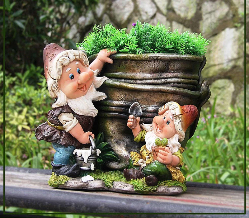 A whimsical garden gnome planter featuring two cheerful gnomes gardening around a large bronze-colored pot filled with green plants