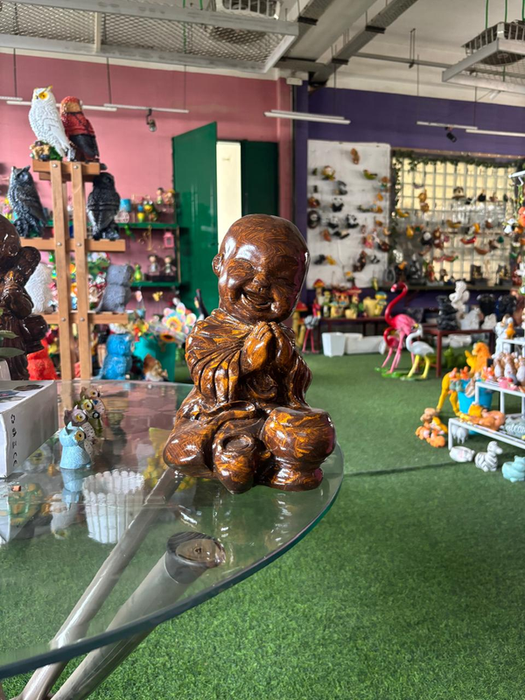 13-inch tall handcrafted wooden-finish smiling monk figurine in a prayer pose, displayed on a glass table for home zen decor.
