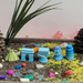 A set of five blue and green miniature landmarks, including a pyramid, an arch, a column, a Moai statue, and the Leaning Tower of Pisa, arranged in a decorative tray with sand and colorful stones.