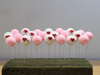 A row of miniature pink and white round balloon picks inserted into a green foam base. The white balloons feature red hearts and "I U" text, while the pink balloons are solid colors.