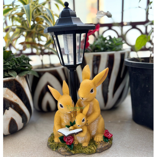 Solar powered rabbit family garden statue reading a book under a black lantern on a grass background with dimensions shown.