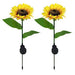 Two realistic artificial sunflower garden stakes with integrated solar panels and silver metal ground spikes, isolated on a white background.