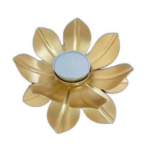 A golden metal flower-shaped tealight candle holder with a white unscented candle.
