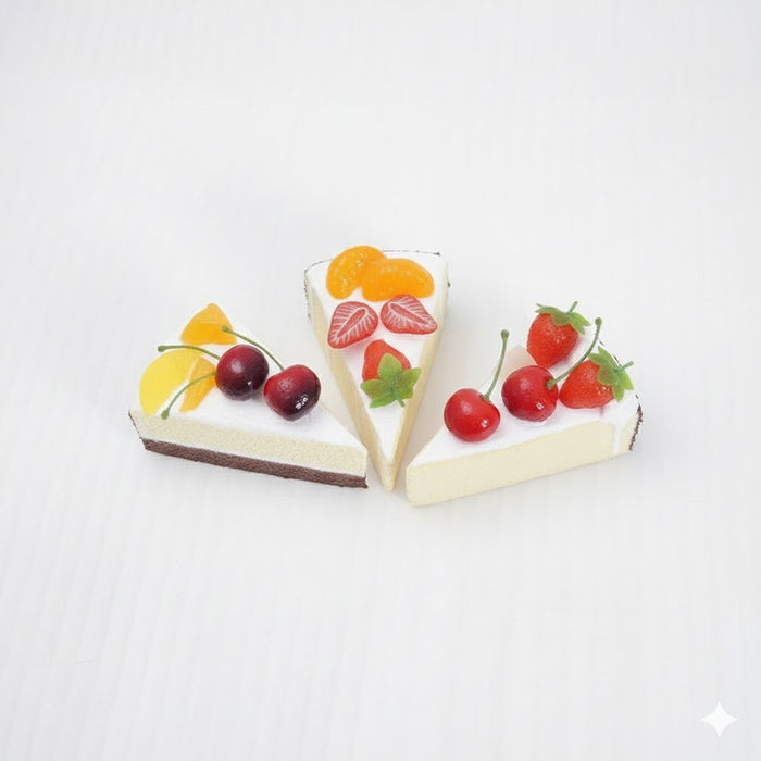 Set of 3 realistic non-edible cake slices with assorted fruit toppings (cherries, strawberries, blueberries, peaches) for decorative display or photography props.