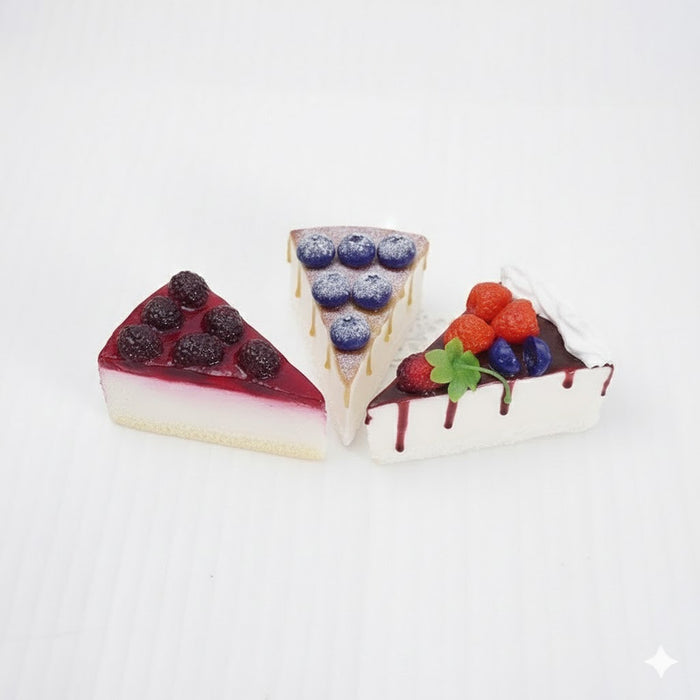 Set of 3 realistic non-edible cake slices with assorted fruit toppings (cherries, strawberries, blueberries, peaches) for decorative display or photography props.