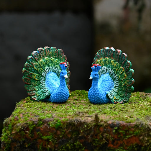 Two bright blue miniature peacock figurines with fully displayed green and gold tails 