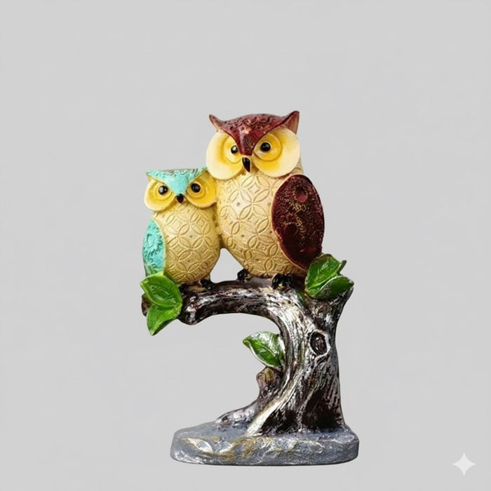 Two owl showpieces, perched  together on a sculpted tree branch showpiece.