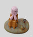 Little monk figurine in orange robe sitting on a stone base, cute zen buddha statue for home office desk and fairy garden decor.