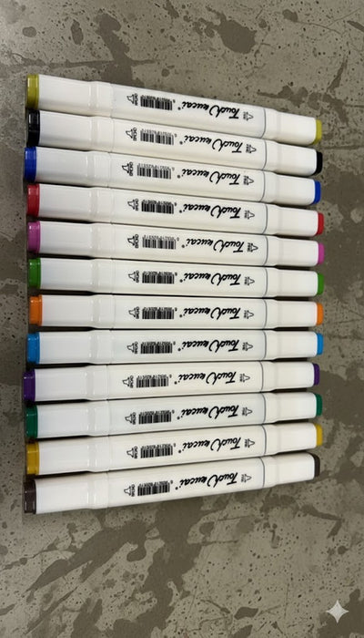 A set of 12  Dual Tip Art Sketch Markers lined up on a white background, showing the caps and barrels. The markers feature both Fine and Broad tips and have a color-coded end cap, displaying vibrant colors including purple, green, blue, yellow, orange, red, and black.