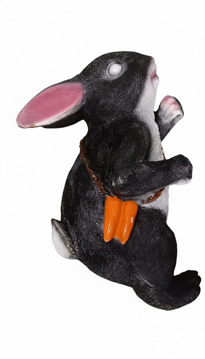 Black and white rabbit hanging ornament with pink inner ears, wearing a brown chain necklace from which hangs a small, orange carrot-shaped purse/pouch.