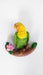 Hand-painted resin figurine of a yellow-headed, green parrot perched on a brown branch with a pink flower.