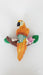 A small, brightly colored ceramic or clay figurine of an orange and yellow macaw or parrot perched on a brown branch with green leaves and pink and white tropical flowers.