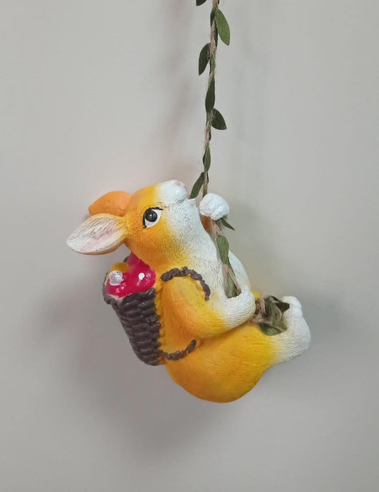 Swinging bunny garden ornament holding a basket of red flowers/mushrooms.