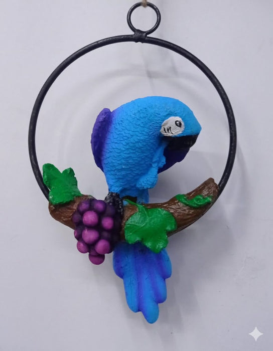 Blue macaw parrot sculpture on a vine with purple grapes, hanging on a black metal ring.