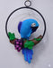 Blue macaw parrot sculpture on a vine with purple grapes, hanging on a black metal ring.