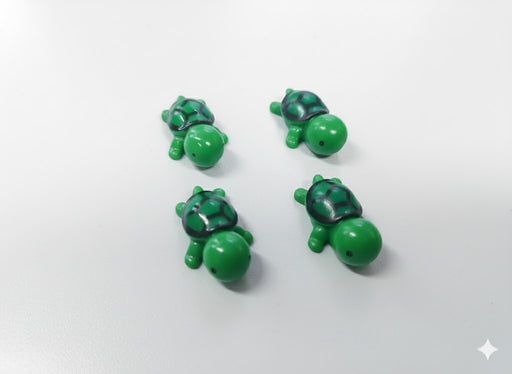 Four small, green, miniature plastic toy turtles with black and green shells on a white surface.