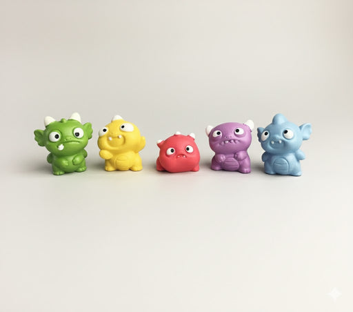 Five colorful collectible creature  figurines: green, yellow, red, purple, and blue, displayed on a clean off-white background.