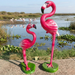Two vibrant pink resin flamingo garden statues with detailed feathers and black beaks