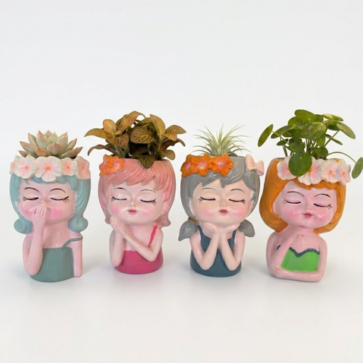 A row of four cute resin girl face planters in pastel colors (mint, pink, grey, and orange) featuring closed eyes and hand-painted floral headbands, each holding a different small indoor plant including succulents and air plants.