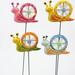 Four colorful decorative snail garden stakes with spinning windmill shells in pink, yellow, orange, and blue, mounted on thin metal poles against a neutral background.