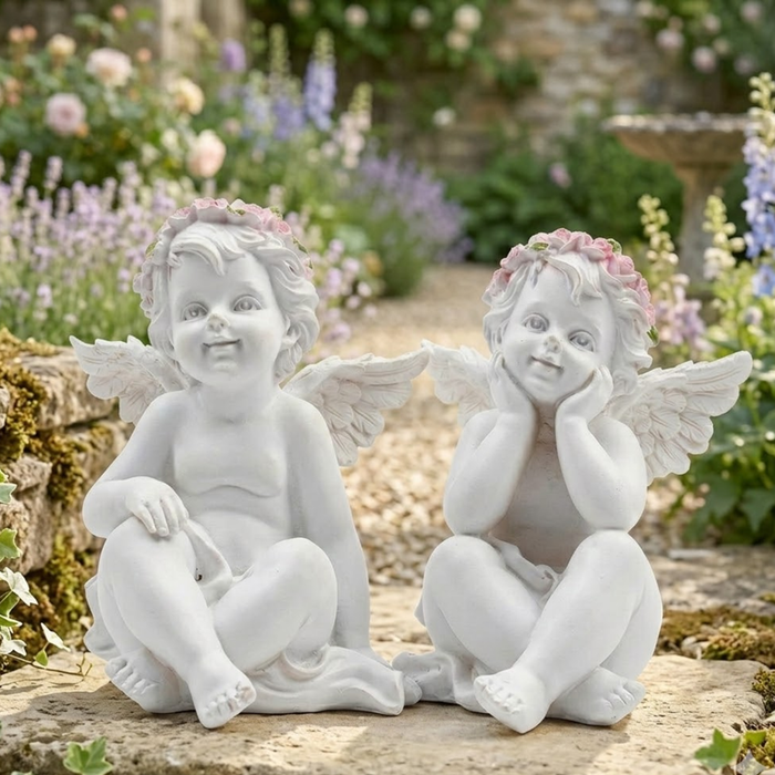 Pair of white resin cherub angel figurines with pink flower crowns and wings, sitting side-by-side on a plain white background.