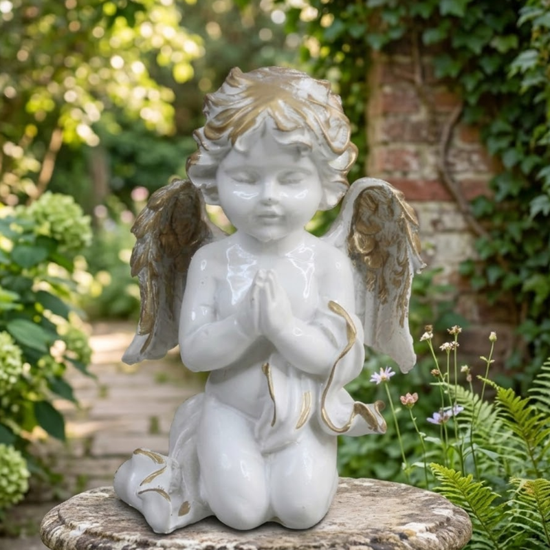 An angel cherub figurine kneeling in prayer with gold-trimmed wings and hair.