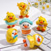 A set of 5 cute miniature yellow duck figurines in various playful poses, including one in a raincoat, one with a swim ring, and one playing a guitar