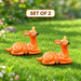 A pair of cute miniature orange spotted fawn deer figurines resting outdoors,