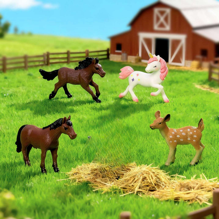 Miniature toy set featuring two brown horses, a spotted baby deer, and a magical unicorn standing in a grassy meadow with a red barn in the background.