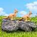 A miniature kangaroo figurine standing on a dark grey rock surrounded by artificial green grass