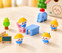 “A colorful 9-piece kawaii miniature playset featuring cute cartoon characters in yellow hats, a mini blue desk and chair, a toy elephant, a green tree, and a blackboard on a wooden tabletop.”
