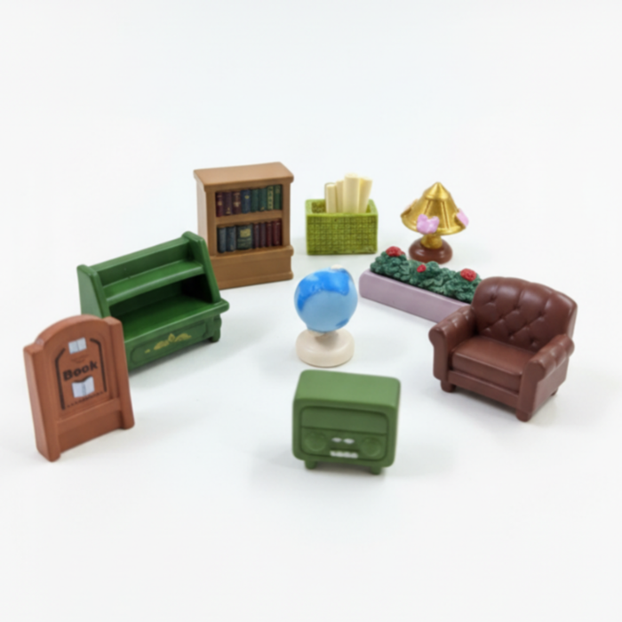 9-piece miniature library furniture toy set including a brown leather-style armchair, green shelves, bookshelf, radio, lamp, planter, paper basket, book sign, and mini globe