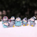 Set of 6 cute miniature penguin figurines in different playful poses displayed on a snowy white surface