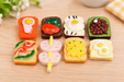 A set of 8 colorful miniature toast and food charms featuring fried eggs, spreads, and skewers